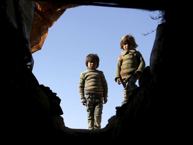 Crianças sírias são vistas na entrada de abrigo improvisado em uma caverna em Om al-Seer, no sábado (26) (Foto: Reuters/Khalil Ashawi)