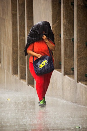 Mulher se protege da chuva em São Paulo (Foto: Adailton Damasceno/Estadão Conteúdo)