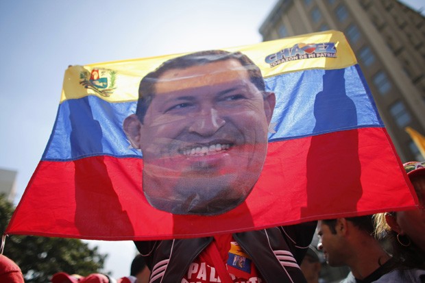 Simpatizante segura bandeira da Venezuela com foto de Hugo Chávez. Boatos sobre a saúde do presidente reeleito persistem após ausência do líder. (Foto: Jorge Silva/Reuters)
