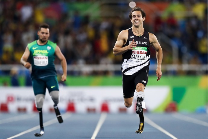 Descrião da imagem: Liam Malone corre na eliminatória dos 200m T44 com Alan Fonteles ao fundo (Foto: Hagen Hopkins/Getty Images for the New Zealand Paralympic )