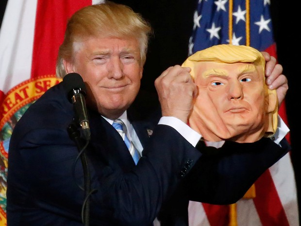 Donald Trump brinca com uma máscara no palco de um comício em Saratosa, na Flórida, na segunda (7) (Foto: Reuters/Carlo Allegri)