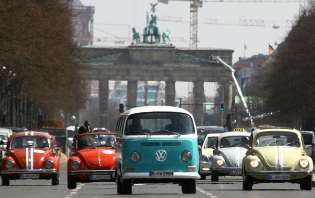 Uma kombi e fuscas antigos desfilam na frente do Portão de Brandemburgo, em Berlim; empresa criou um tour pela cidade nos carros da Volkswagen (Foto: Steffen Trumpf /AFP)