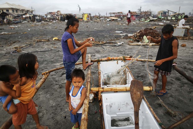Família limpa uma rede de pesca em barcoimprovisado nas Filipinas (Foto: Damir Sagolj/Reuters)