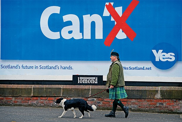 NACIONALISMO Um escocês em Glasgow, com seu kilt e seu cão, passa por um cartaz da campanha pelo “sim”, a favor da separação da Escócia do Reino Unido (Foto: Jeff J Mitchell/Getty Images)