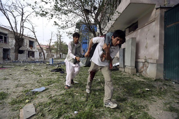 Dupla carrega outro policial ferido no atentado seguido de tiroteio na capital afegã (Foto: Omar Sobhani/Reuters)