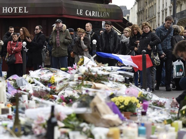 Pessoas fazem um minuto de silêncio em frente ao restaurante Le Carillon, na esquina das ruas Bichat e Alibert, em Paris. O restaurante foi alvo dos ataques (Foto: Eric Feferberg / AFP)