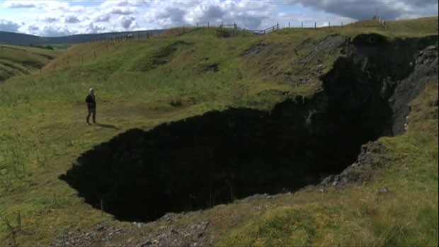 As rachaduras no chão indicam que a cratera, tão alta que se assemelha a um precipício, pode crescer ainda mais nas próximas chuvas. (Foto: BBC)