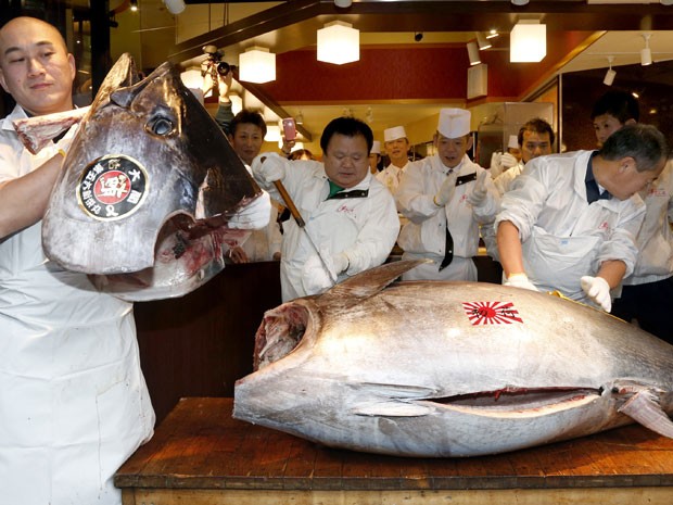 O japonês Kiyoshi Kimura (segundo a partir da esquerda) corta o atum bluefin de 230 kg comprado por R$ 166 mil no tradicional primeiro leilão do ano no mercado de Tsukiji, em Tóquio (Foto: Shizuo Kambayashi/AP)