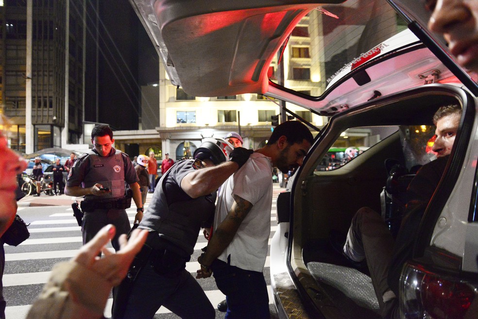 Homem é detido na Avenida Paulista, em São Paulo, após confronto durante protesto de contrários e favoráveis à Lei de Migração no Brasil na noite de terça-feira (2) (Foto: Cris Faga/Fox Press Photo/Estadão Conteúdo)