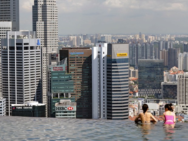 Hóspedes do hotel Marina Bay Sands, em Cingapura, observam a cidade de uma piscina com lateral que termina em queda d'água, no topo do edifício. (Foto: Roslan Rahman/AFP)