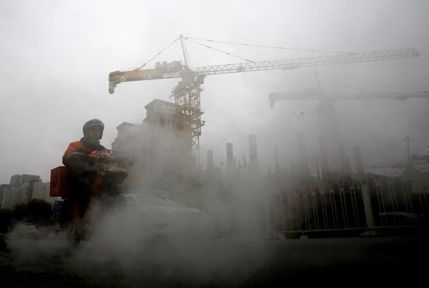 Homem usa bicicleta elétrica em meio a zona de construção com grande poluição em Pequim, na China, nesta segunda-feira (9) (Foto: Andy Wong/AP)