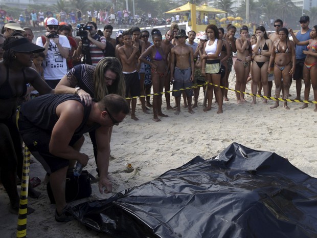 Viúva de Eduardo Marinho, Eliane e o cunhado, João Tinoco, reconhecem o corpo na Praia de São Conrado (Foto: Ricardo Moraes/Reuters)