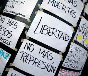 Cartazes pedindo liberdade de expressão e fim da repressão são colados em frente ao escritório da ONU em Caracas, na Venezuela (Foto: Fernando Llano/AP)