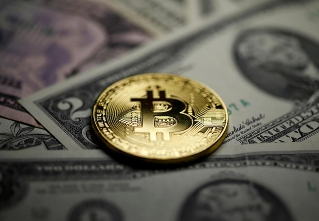 Moeda de Bitcoin aparece próxima a notas de dólar  (Foto: Dado Ruvic/Reuters)