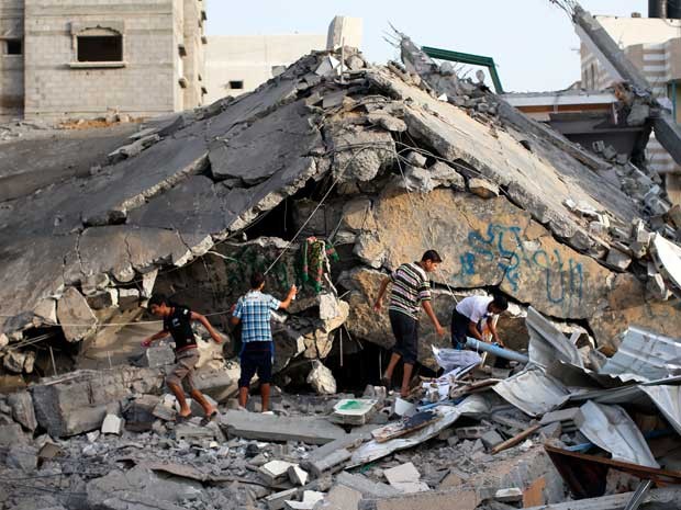 Palestinos inspecionam escombros de uma mesquita destruída após um ataque militar israelense no campo de refugiados de Nusseirat, no centro da Faixa de Gaza. (Foto: Thomas Coex / AFP Photo)