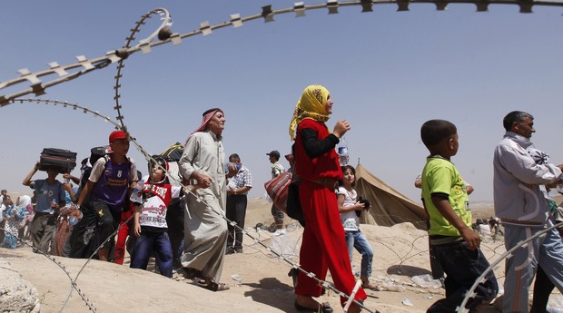 Há muitas mulheres e crianças entre os refugiados que atravessam a fronteira da Síria com o Iraque (Foto: AP Photo/Hadi Mizban)