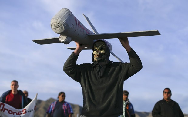 Manifestante mascarado carrega um modelo de drone usado pela Força Aérea nos EUA (Foto: Julie Jacobson/AP) Manifestante mascarado carrega um modelo de drone usado pela Força Aérea nos EUA (Foto: Julie Jacobson/AP)