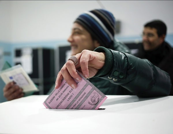 Mulher coloca voto na urna em sessão de votação em Roma, nesta domingo (24). (Foto: Yara Nardi/Reuters)