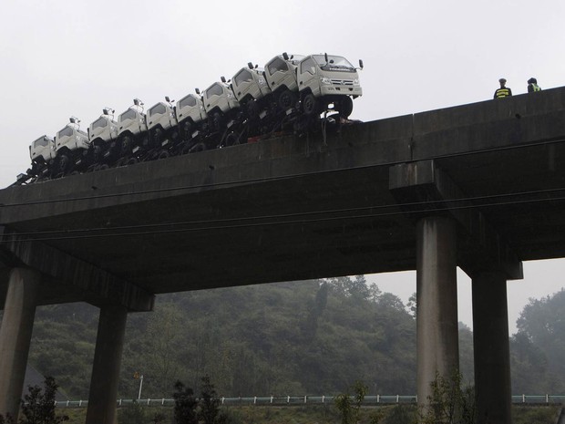 Caminhões enfileirados sobre o compartimento de carga de um caminhão maior ficaram à beira de despencar de uma ponte em Kaili, na província chinesa de Guizhou. O motorista perdeu o controle e bateu contra a mureta. Ninguém ficou ferido. (Foto: Reuters/Stringer)