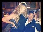 De vestido curtinho, Mariah Carey senta no colo do marido em festa