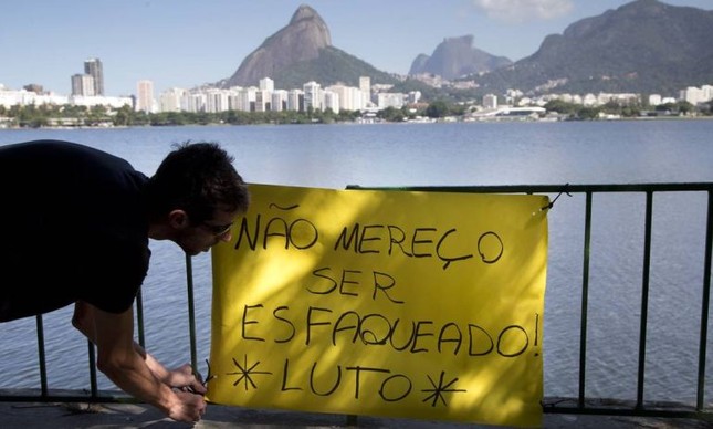 Alexandre Maurel de Azevedo Rodrigues coloca um cartaz de protesto em frente ao local do assalto (Foto: Márcia Foletto / Agência O Globo)