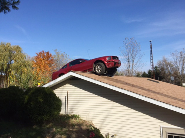 Carro vai parar em telhado de casa em acidente nos EUA (Foto: Michigan State Police via AP)