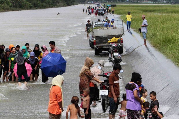 Moradores caminham por áreas alagadas na província de Pattani, na Tailândia (Foto: Surapan Boonthanom/Reuters)