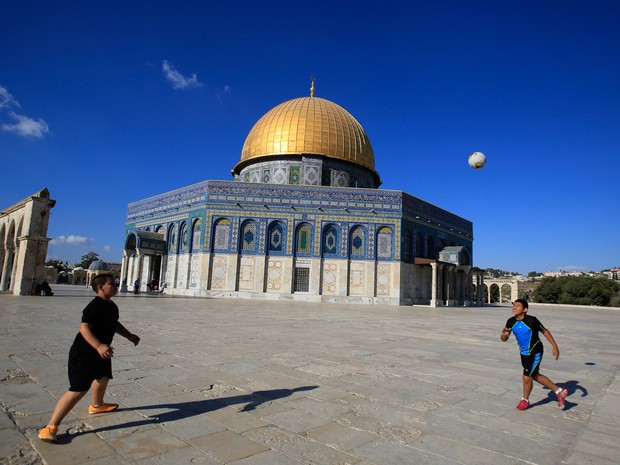 Meninos palestinos jogam futebol em frente à mesquita Domo da Rocha em Al-Aqsa, na cidade antiga de Jerusalém (Foto: Hatem Moussa/AP)