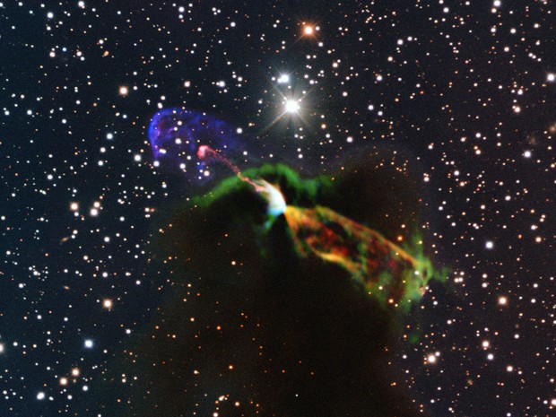 Telescópio no Atacama registrou o nascimento de uma nova estrela.  Os raios laranja e verde, na parte inferior direita, correspondem um grande jato energético afastando-se da Terra. À esquerda estão os raios rosa e roxos, que são observados em luz visível (Foto: AP Photo/ESO/ALMA)