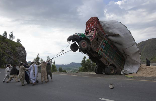Em abril de 2012, homens usaram cordas para tentar puxar um caminhão que havia empinado por estar sobrecarregado em uma estrada em Dargai, no distrito de Malakand, cerca de 165 km da capital Islamabad, no Paquistão (Foto: Mian Khursheed/Reuters)