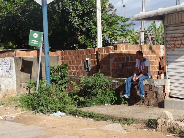 Passageiro espera coletivo sentado em muro na Avenida Perimetral, que liga Recife e Olinda (Foto: Penélope Araújo/G1)
