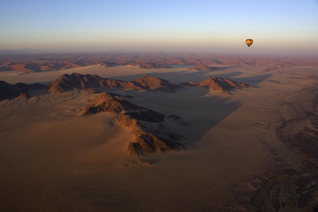 Passeio de balão sobrevoa a paisagem de dunas vermelhas ao sul do deserto da Namíbia, na África (Foto: Divulgação)