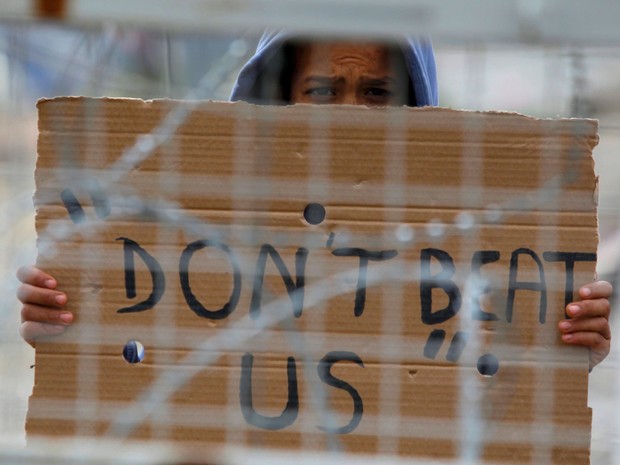 Migrante mostra cartaz com a mensagem â€˜NÃ£o batam na genteâ€™ em protesto na fronteira da GrÃ©cia com a MacedÃ´nia, perto de Idomeni, na manhÃ£ deste domingo (27) (Foto: Ognen Teofilovski/ Reuters)