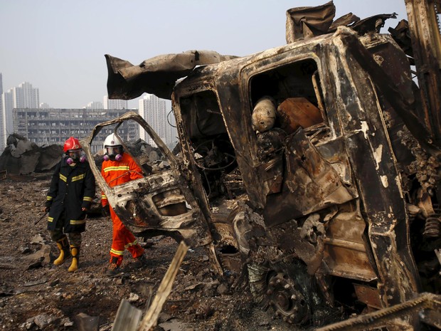 Bombeiros caminham próximo a um caminhão danificado no local das explosões de quarta-feira em Tianjin, na China (Foto: REUTERS/China Daily) Bombeiros caminham próximo a um caminhão danificado no local das explosões de quarta-feira em Tianjin, na China (Foto: REUTERS/China Daily)