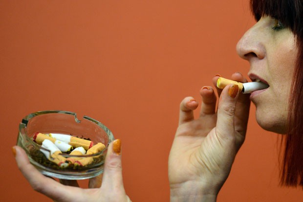 Mulher come cigarro comestível feito de pão de gengibre. (Foto: Ben Stansall/AFP)