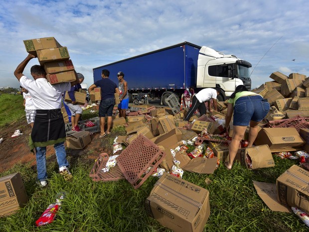 Pessoas saqueiam carga de um caminhão que transportava alimentos e tombou na lateral da Via Dutra, na altura do km 124, sentido São Paulo-Rio de Janeiro, em Caçapava (SP). Ninguém se feriu no acidente (Foto: Lucas Lacaz Ruiz/Estadão Conteúdo)