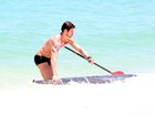 Com prancha personalizada, José Loreto faz stand up paddle na praia