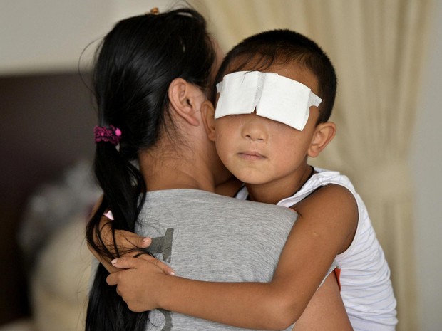 Garoto que teve olhos arrancados é visto no colo da mãe em um hospital de Taiyuan, na China. As autoridades da China suspeitam que a mulher que arrancou os olhos de um menino de 6 anos era a tia dele. Ela se matou 6 dias depois, segundo a mídia estatal. (Foto: Reuters/Stringer)