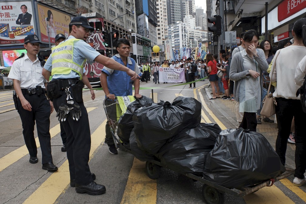 Policiais pedem a um funcionário da limpeza que se afaste do local das manifestações pelo 1º de maio, dia do trabalho, em Hong Kong. — Foto: Kin Cheung/AP
