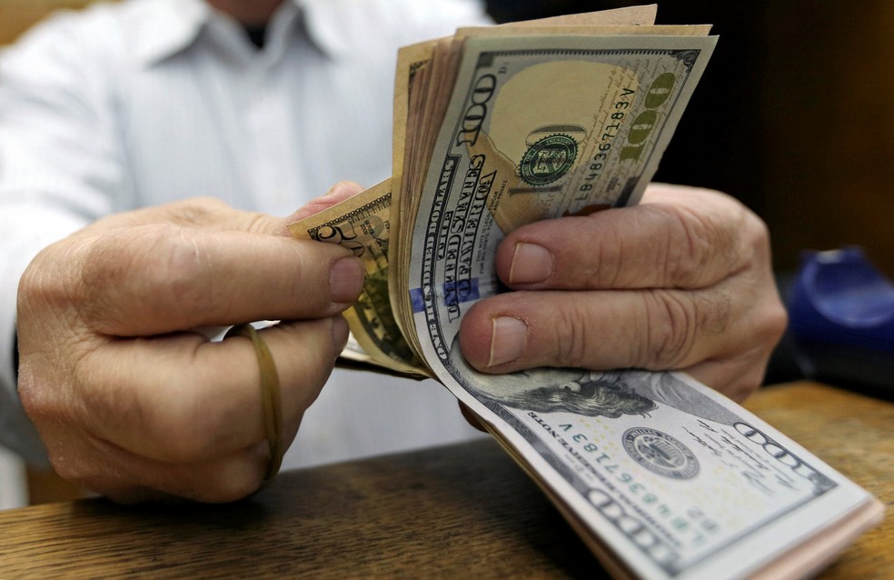 Homem conta notas de dólar em casa de câmbio no Cairo, Egito. (Foto: Reuters)