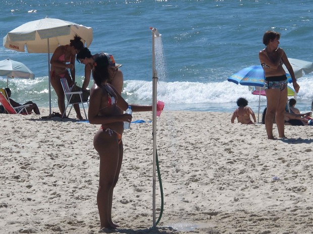 Mulher toma banho de chuveiro na praia da Barra da Tijuca (Foto: Gabriel Barreira / G1)