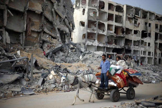 Palestinos passam por prédio destruído ao voltar para Beit Lahiya nesta quarta-feira (6) (Foto: Suhaib Salem/Reuters)