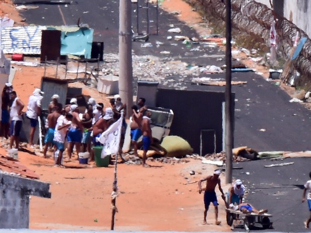 19/01 - Um preso ferido é puxado por outros em um carrinho durante um confronto de facções na penitenciária de Alcaçuz, perto de Natal, no Rio Grande do Norte (Foto: Josemar Gonçalves/Reuters)