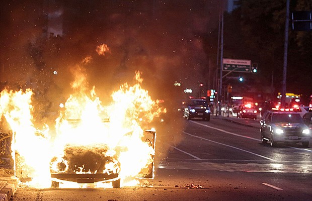 Carro pega fogo durante protesto em São Paulo neste sábado (25) contra a Copa do Mundo. (Foto: Miguel Schincariol/AFP)
