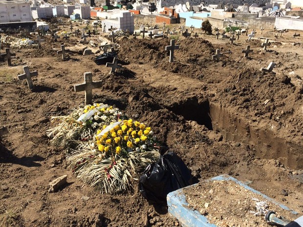 Sacos pretos são vistos ao lado de várias covas recém-abertas (Foto: Janaína Carvalho / G1)