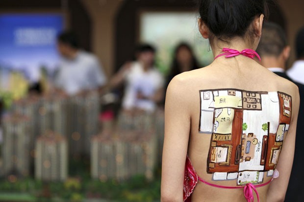 Modelo exibe pintura corporal em forma de planta de apartamento em feira na China (Foto: Cui Genyuan/Xinhua/AP)