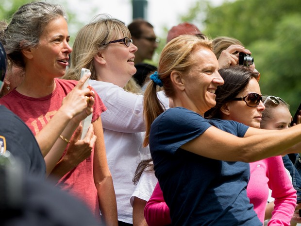 Frequentadores do Central Park fotografam Barack Obama durante o passeio do presidente com suas filhas, Sasha e Malia, no sábado (18) (Foto: AP Photo/Andrew Harnik)