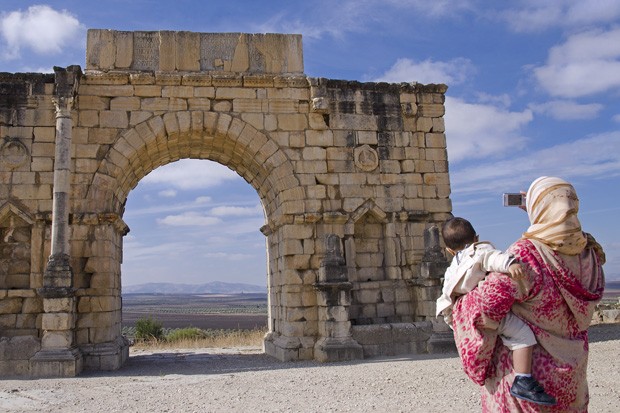 Uma senhora marroquina, com um bebê nos braços, não hesita em fotografar o Arco de Caracala ou Arco do Triunfo, construído no ano 217 (Foto: Haroldo Castro/ Época)