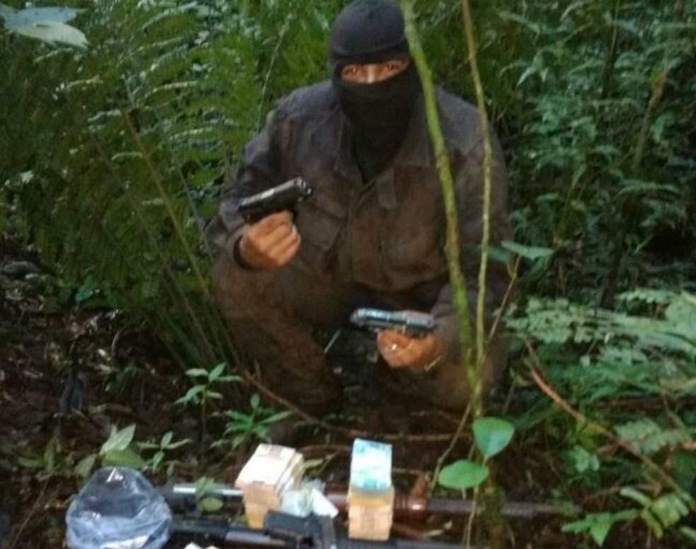 Suspeito com arma e dinheiro possivelmente roubado em foto feita com o celular de Fazenda (Foto: Polícia Civil/Divulgação)