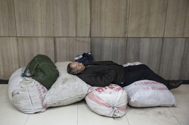 Passageiro usou bagagem para montar 'cama king size' em estação de trem em Pequim, na China (Foto: Alexander F. Yuan/AP)